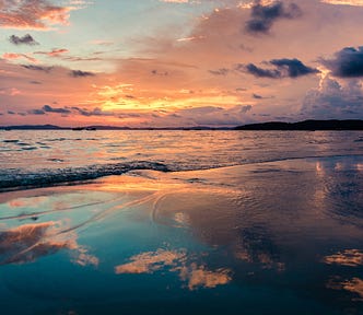 Warm redish glow in the clouds over the ocean at sunset