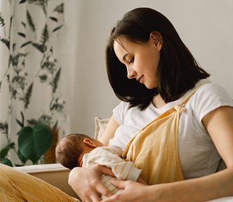 A mother with dark hair wearing yellow overalls breastfeeding her baby. Jessie Waddell.