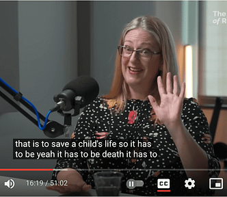 quirky video still of Helen Joyce putting her hand up and looking astonished with the closed caption: that is to save a child’s life so it has to be yeah it has to be death it has to