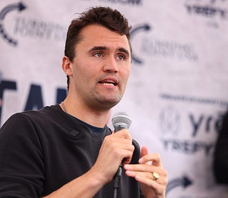 Charlie Kirk holding a microphone during a public debate.