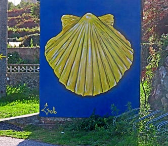 Large blue painted wall with a giant yellow scallop shell on it.
