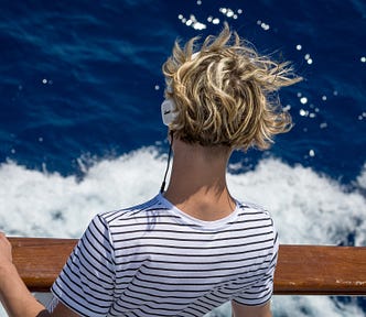 Man with headphones looking into the waves during a windy day