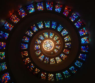 Stained glass domed ceiling with spiraling windows and a bright central window