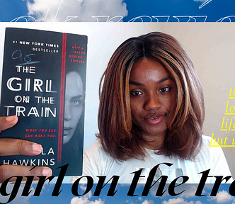 Black woman holds up book titled “The Girl on the Train”