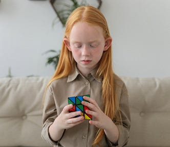 Little girl solving a rubric’s cube and exercising her brain