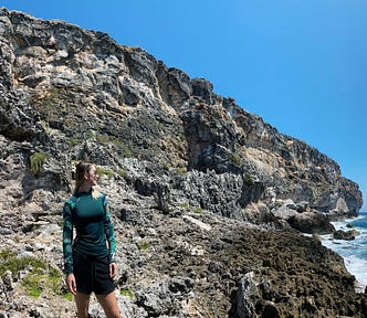 picture of a woman in front of a cliff beside the ocean