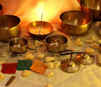 An altar with Tibetan singing bowl, chimes and prayer flags in front of a fire