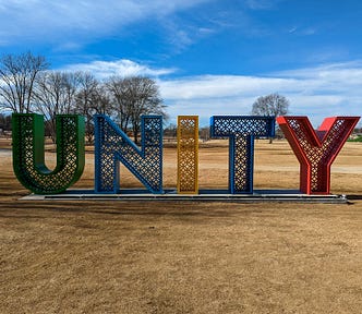 Large metal sign in a field reading U N I T Y