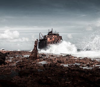 Waves crashing on rock with a derelict building in the background