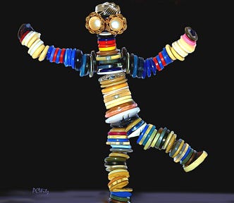The Button Guy. In front of a pitch black background, different colorful varieties of buttons are stacked and linked together to form a person with arms and legs flung out in jubilation. Two peril buttons with gold fringes form eyes and a wavy button on top of his head looks like a silver Trump wig.