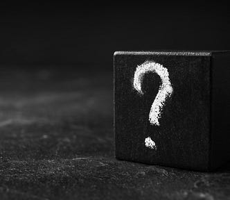 A wooden cube with a question mark on a table