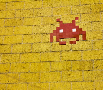 Red tiles form an alien head on a yellow brick wall.