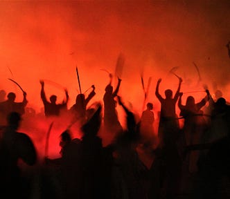 silhouette against red smoky background of people with arms raised in battle