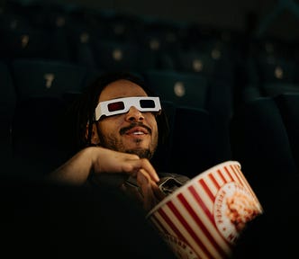 A man with a bowl of popcorn seeing a movie at a cinema