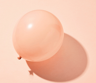 A pink balloon on a pink surface.