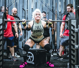 older woman triumphantly lifting a heavy barbell (senior power)