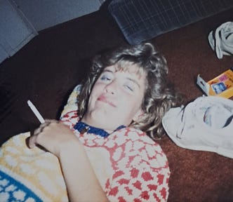 Author circa 1986, on the floor with a cigarette in hand, droopy drunk eyes, lying next to a white sneaker and a package of Kodak Disc film.