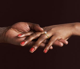Closeup of a Black woman’s hand with an engagement ring.
