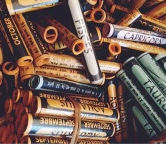 A mixed bunch of horoscope “star scrolls” scrolls piled together, some with rubber bands. You can see several horoscope signs like Taurus, Aquarius, Capricorn, Pisces, etc…