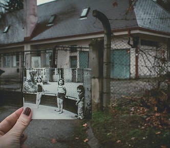 An old photo is held up in front of the building where it was taken a long time ago.