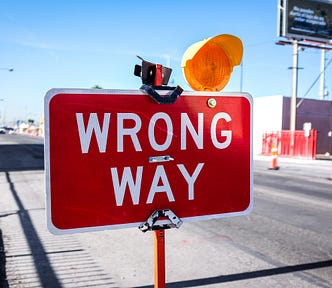 A sign board displaying ‘Wrong Way’ by the roadside