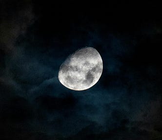 A captivating view of the gibbous moon shining through dark clouds in the night sky over Rio de Janeiro.