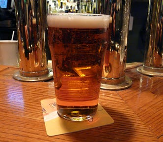 a full pint glass of beer sitting on a wooden bar