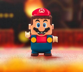 A super mario lego in red, yellow and blue stands on a play ground