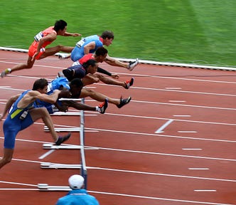Athletes jumping over a hurdle in a race