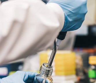 Scientist Injecting Red Liquid Into Bottle Photo