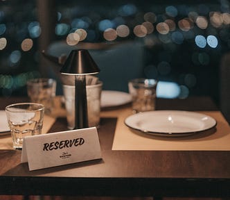 Fine dining table setting with a reserved sign sitting on it.