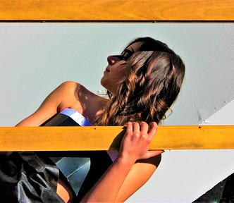 profile of girl with brown hair holding wooden frame in front of her