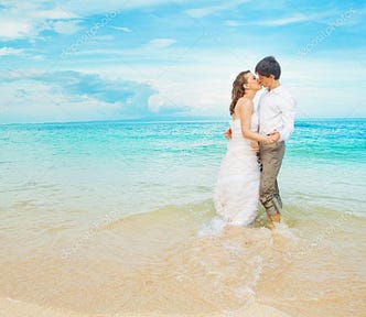 A happy couple kisses on the beach after getting married