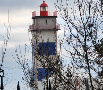 A lighthouse with blue and white stripes and a red top.