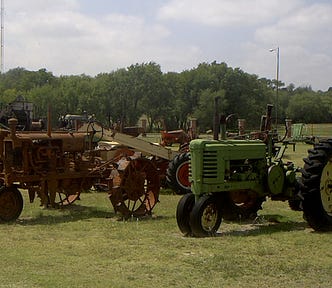 Image of old farm tractor’s lined up in a field on display