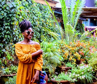 A woman in a yellow dress stands in a botanical garden. The poem “Summer’s Reign in the Botanical Garden” is based around the setting of gardens and includes a character who wears a yellow dress.