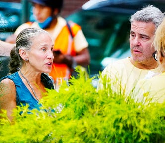 Sarah Jessica Parker and Andy Cohen sitting in a table in an external area