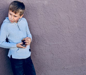 Young boy in blue jacket with Pokemon cards looking skeptically away.