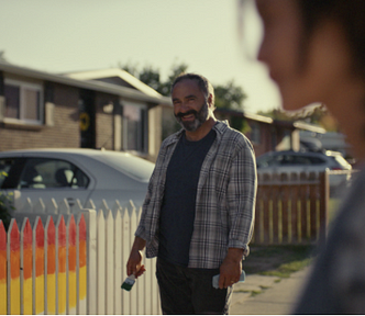 Daughter walking into home. Father smiling near fence, painted in many colors