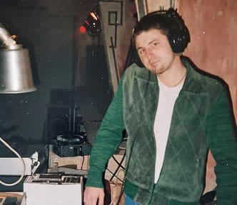 Gentry Bronson DJing at the Roxy Klub in Prague in 1995 wearing a 1960s green zip-up hipster sweater