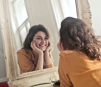 Woman looking into mirror and smiling