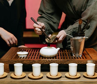 Two people in Japanese robes prepare tea like a Zen tea ceremony.