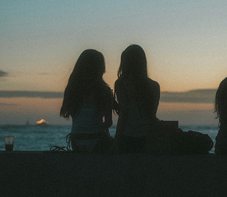 three women watching the sunset by the water, the third slightly out of frame