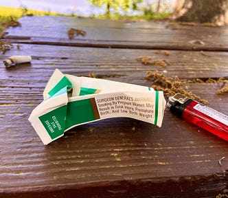 A cigarette butt, lighter, and a crumpled pack of cigarettes.