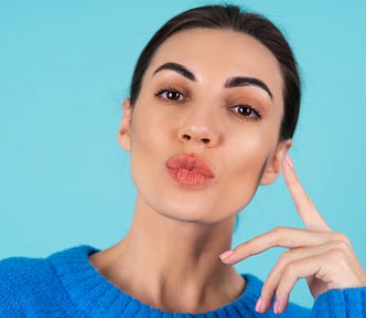 Young woman in a blue knitted sweater with a nude matte lip make-up.