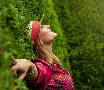 A happy, vital woman wearing a hat smiles in the garden.