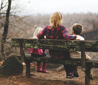 woman sitting on a bench with 2 children