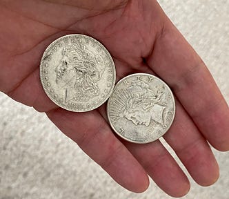 Two old silver dollars in my hand