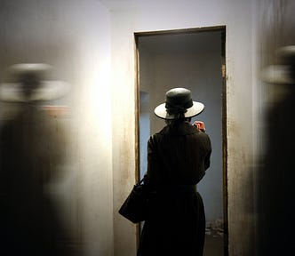 A woman in a hat walks out or in a door.