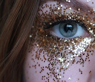 Closeup of woman’s eye with glitter on her face.